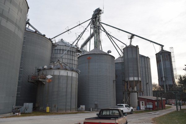 lots of grain bins in a large system with work trucks driving by