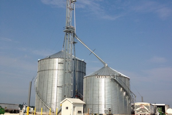 system of two grain bins in front of a blue sky